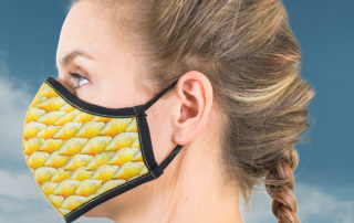 Seitenansicht einer Frau die eine Gesichtsmaske im "Yellow Scales"-Design trägt